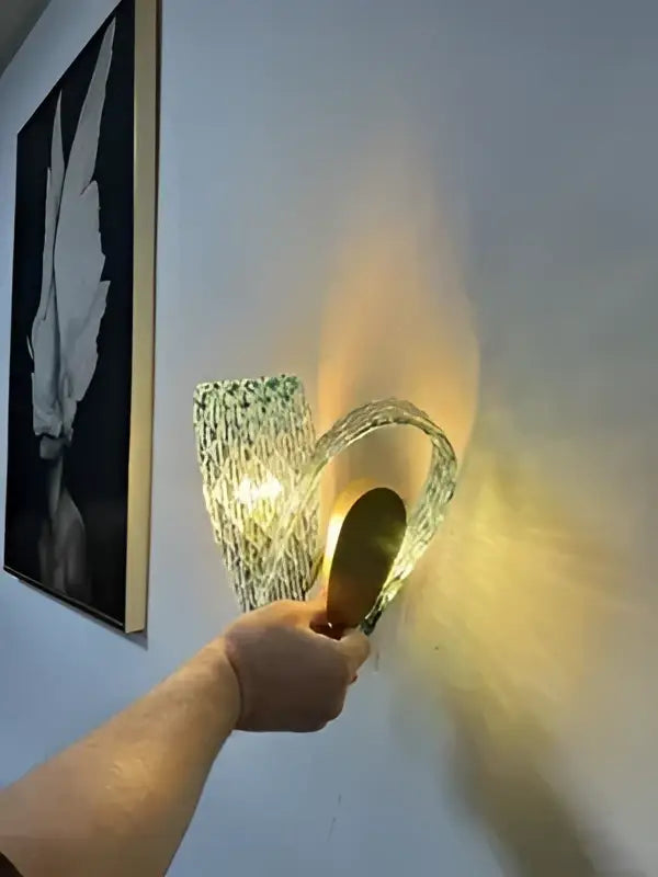 A hand holds a modern blue glass led pendant lamp with curved glass and warm golden metal accents by DecorBites™