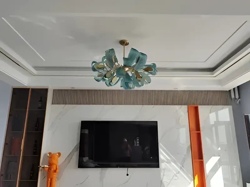 A modern DecorBites™ pendant lamp with translucent teal blue glass LED petals and a gold-toned central frame
