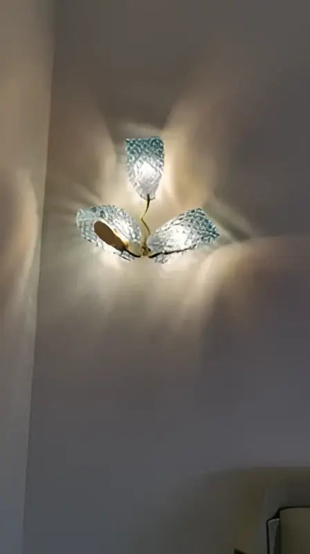 DecorBites blue glass LED pendant lamps feature a three-armed ceiling light with metallic frame and warm glass shades