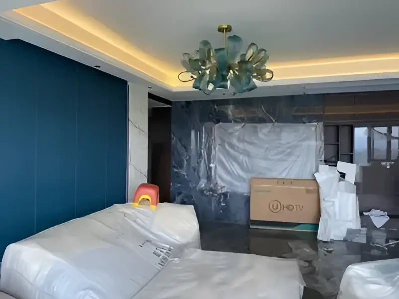 A bedroom with furniture wrapped in plastic featuring decorbites blue glass led pendant lamps for modern lighting