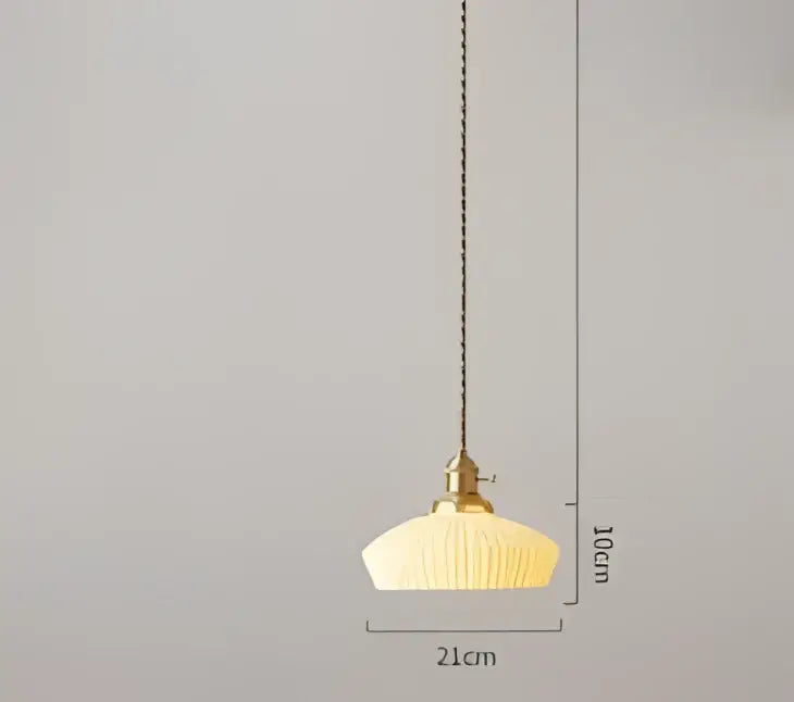 A warm cream-colored pendant light with ribbed glass shade and brass fixture for decorbites blue glass pendant