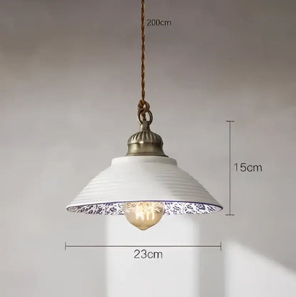 White ceramic pendant light with blue floral rim and antique brass fixture complementing decorbites blue glass pendant