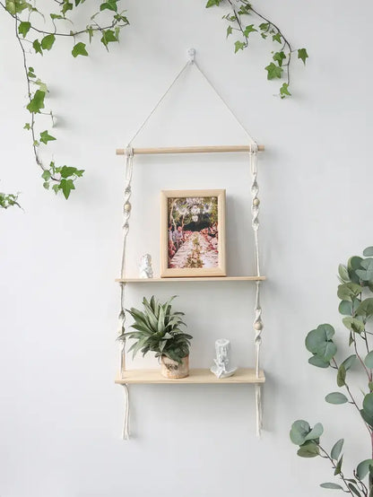 DecorBites™ boho macrame wall shelf with light wood shelves and white rope holding framed photo and potted plant for home decor
