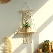 Beige macrame hanging shelf with wooden wall shelf holding potted plant for boho home decor by decorbites