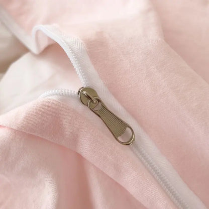 A metallic zipper with a textured pull tab on soft pink fabric of decorbites bow embroidery bedding set with ruffles