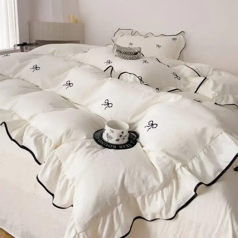 White DecorBites™ bow embroidery bedding set with ruffles featuring black embroidered bow details and matching trim