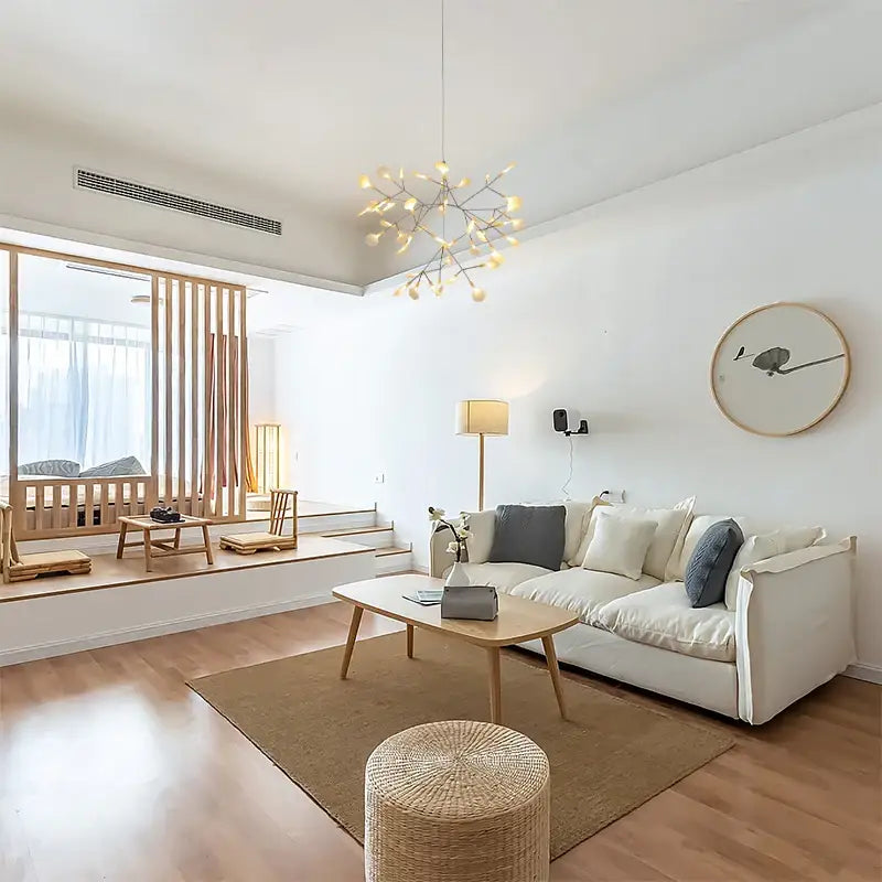 White sofa with gray throw pillows beneath a decorbites™ branch design nordic chandelier in rose gold black finish
