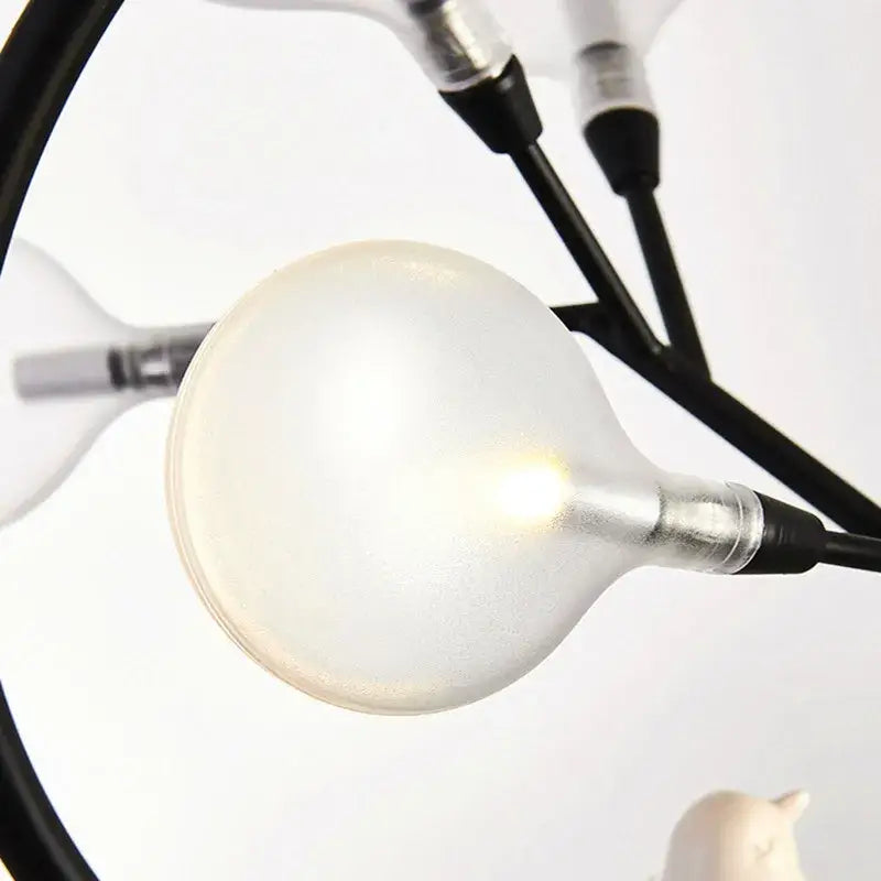 Illuminated frosted glass globe bulb with metallic base attached to black structural arms in decorbites branch iron black gold chandelier
