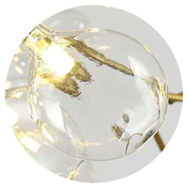 Clear glass globe with golden filament illuminated by warm led lights in decorbites branch iron black gold chandelier