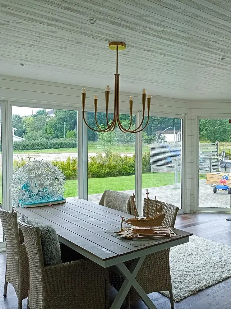 Decorbites brass chandelier for dining room with curved brass-toned arms and exposed bulbs hanging from a central rod