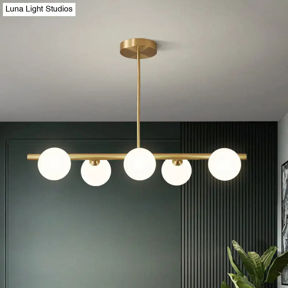 Decorbites brass plated glass sphere island pendant light with five clear white frosted glass globe bulbs in linear design