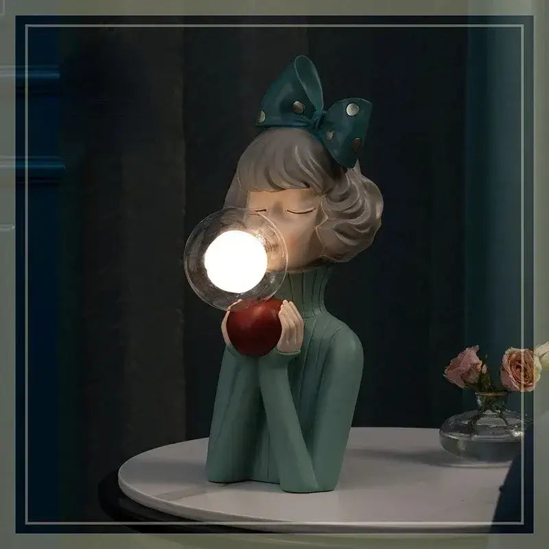 A teal decorbites bubble girl resin night light featuring a girl with a bow holding a red apple and blowing a glowing orb