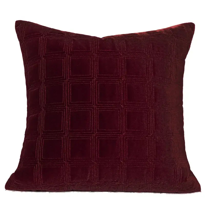 A decorbites burgundy velvet throw pillow with a subtle quilted geometric embroidered grid pattern for bedroom use