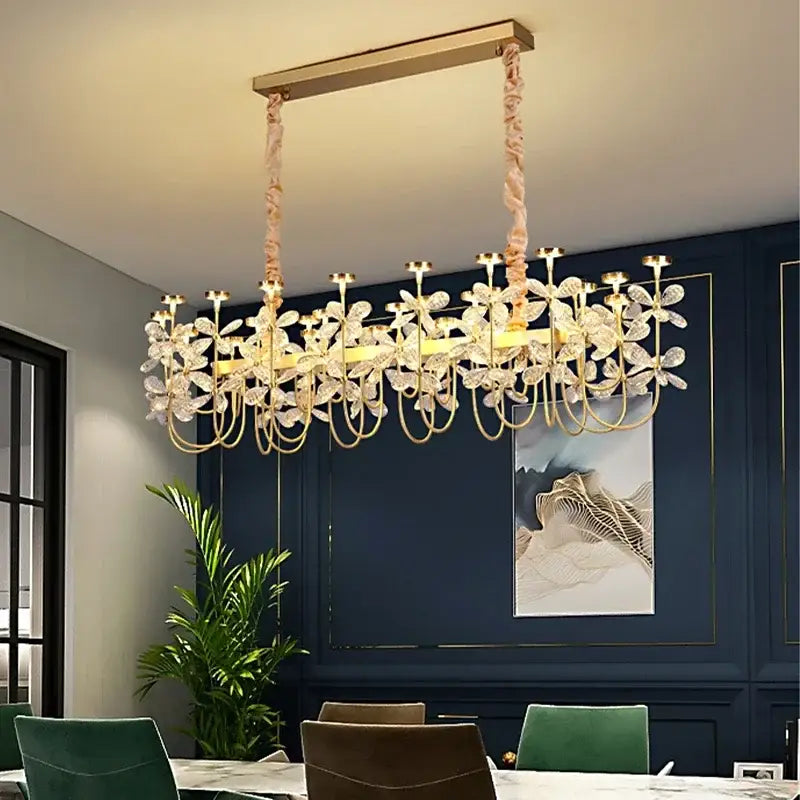 Gold-toned decorbites butterfly chandelier with crystal-encrusted floral design in a sleek rectangular dining room frame