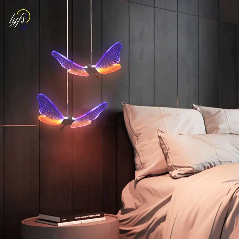 Two glowing decorbites butterfly pendant lights with purple and orange illuminated wings hang in a dining room