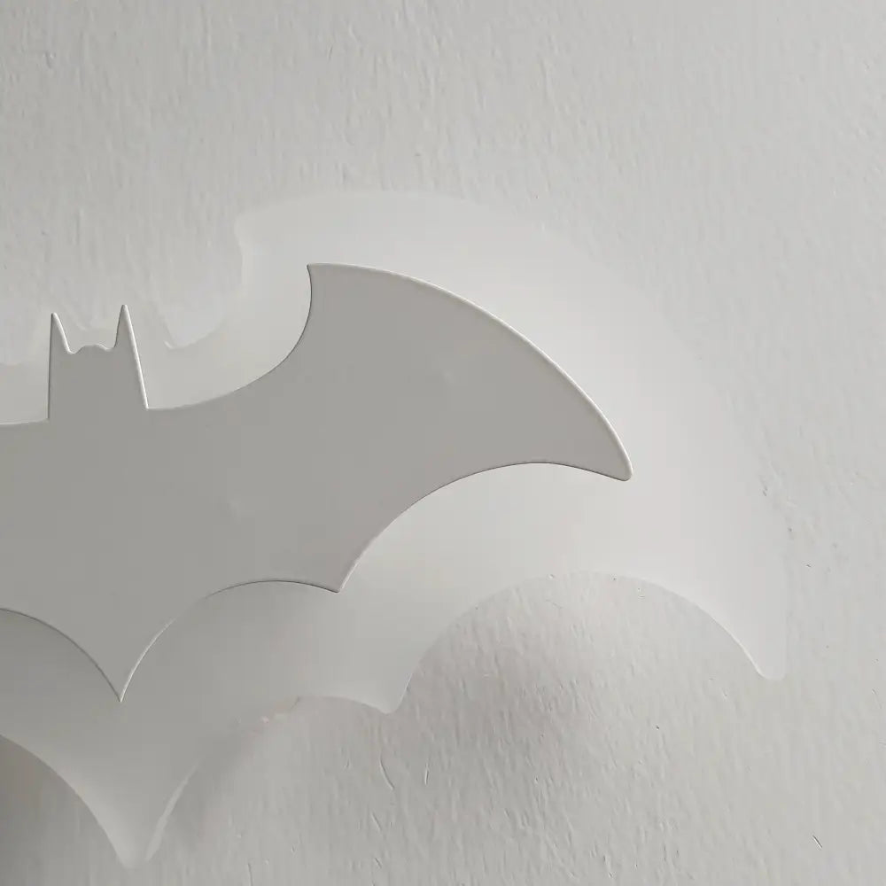 White matte-finish batman logo wall decal featured in decorbites cartoon bat wall lamp with warm yellow acrylic light