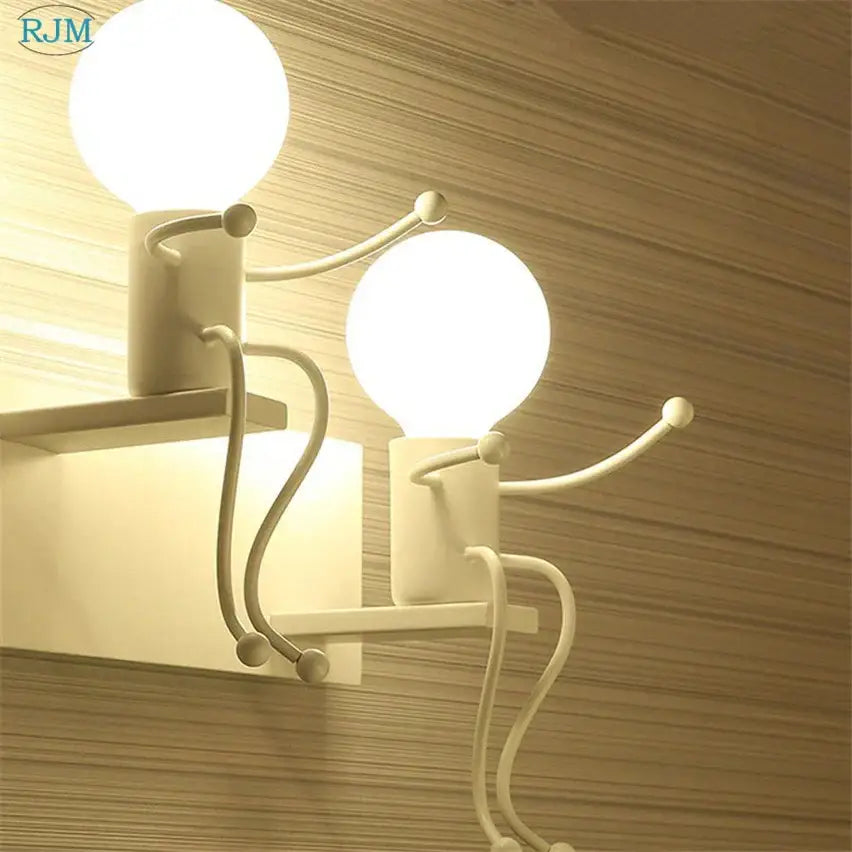 White minimalist wall lamps featuring two stylized cartoon children iron figures by Decorbites for bedroom decor