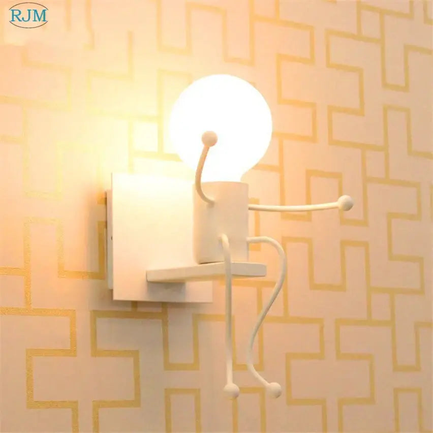 White ceramic wall lamp resembling a seated cartoon children iron figure by Decorbites for bedroom decor
