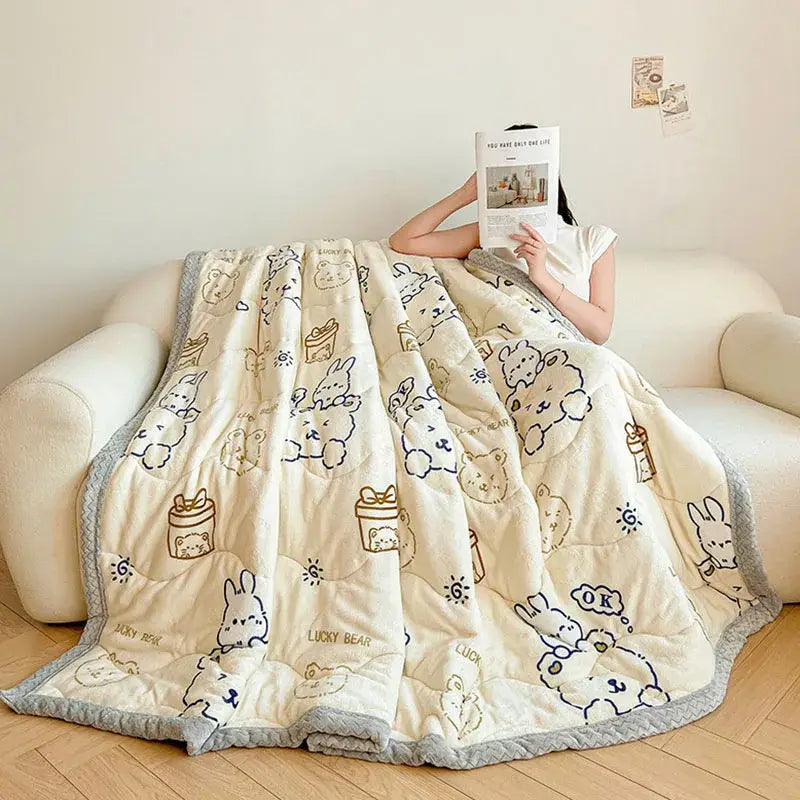 Cream velvet quilted blanket with plush texture and decorbites cartoon print featuring bunnies and gift boxes in navy and gold