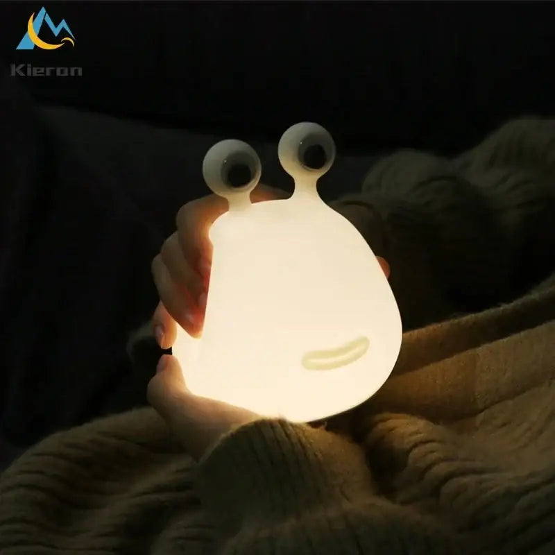 A soft glowing white silicone decorbites cartoon slug night light with large googly eyes for bedroom use