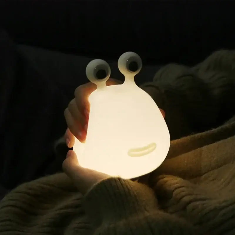 A soft glowing white silicone decorbites cartoon slug night light with large googly eyes and a smiling face