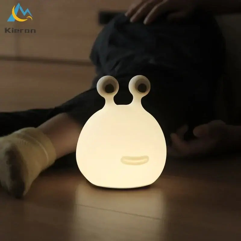 A soft glowing white silicone night light shaped like a cute decorbites cartoon slug with large eyes and smiling face