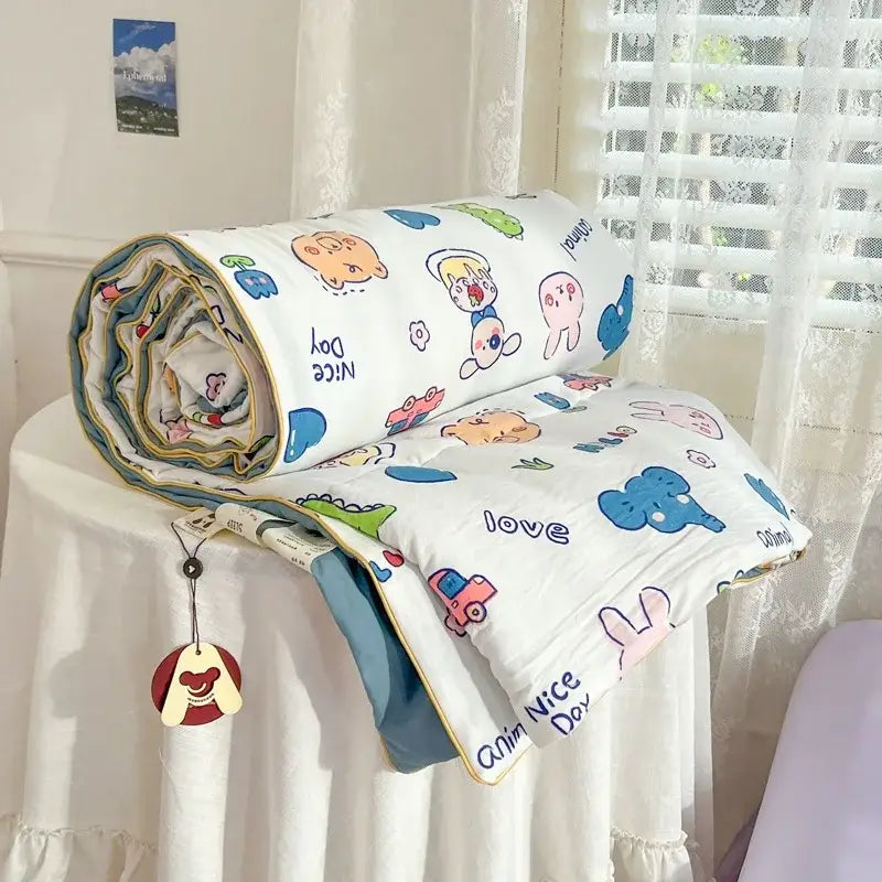 A cozy white decorbites cartoon summer cotton blanket with playful animal prints and blue trim rolled on a table