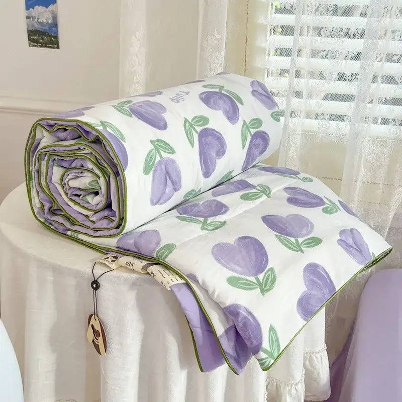 A decorbites cartoon summer cotton blanket with a purple tulip pattern green stems and lavender lining rolled up