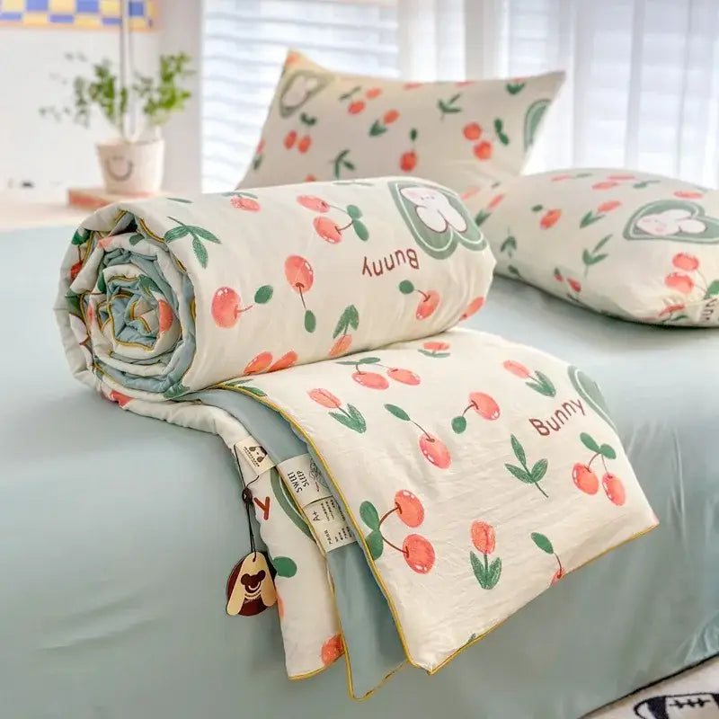 A soft cream-colored cotton decorbites cartoon summer blanket with cherry bunny pattern and light blue trim for bedroom use