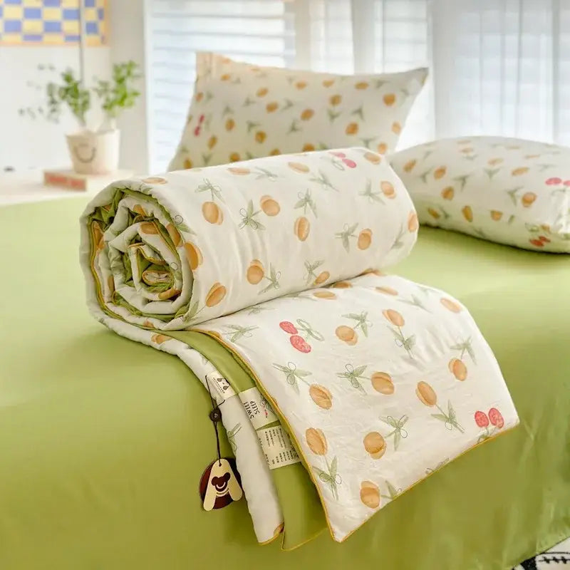 A rolled-up decorbites cartoon summer cream teddy bear cotton blanket with orange fruit pattern and soft green border