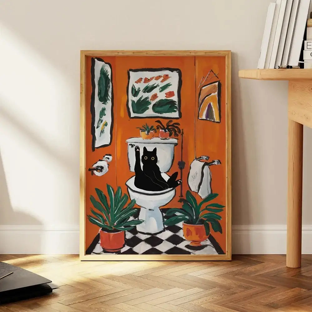 Orange-framed DecorBites™ cat reading wall art showing a black cat on a white toilet with plants and towels on canvas