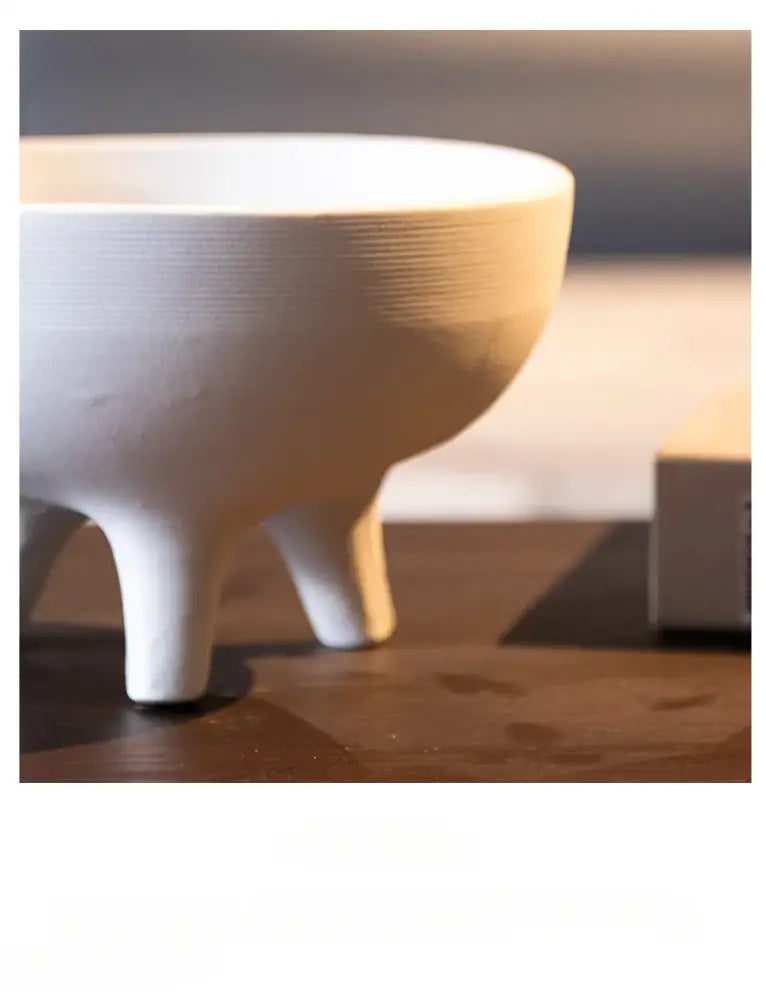 White ceramic flower pot from decorbites with subtle horizontal ridges and tripod stand for decorative use