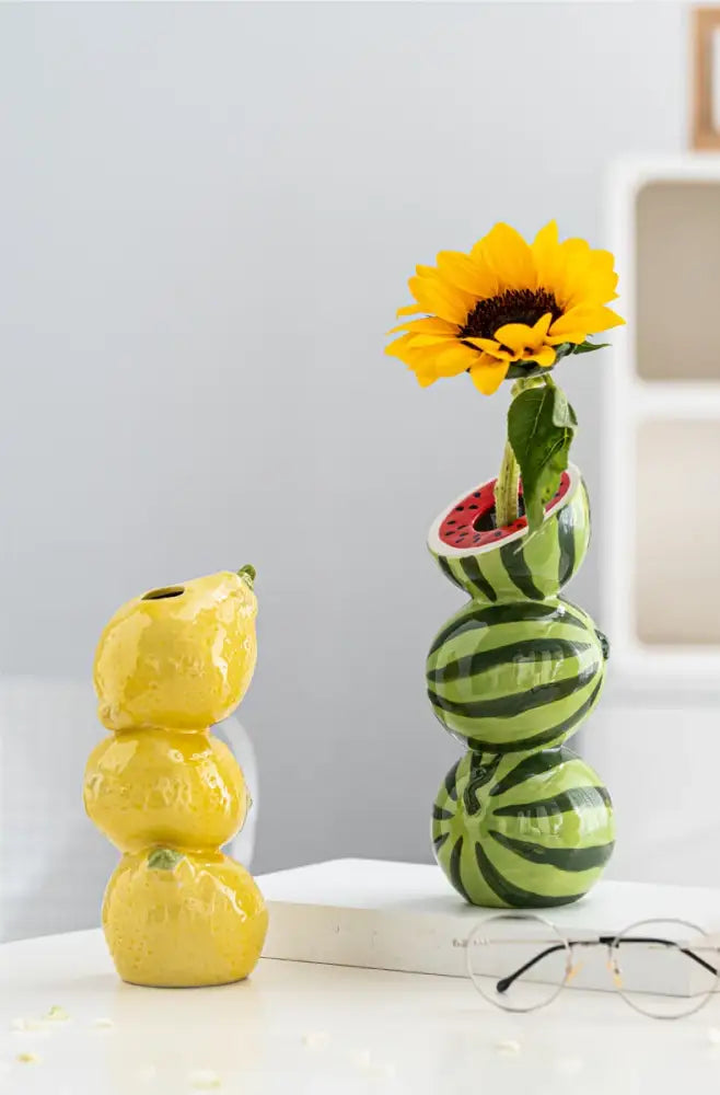 Stacked green and black striped ceramic fruit vase shaped like watermelon holding a yellow sunflower for home and office decor