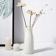 Decorbites™ ceramic-look plastic vase imitation with white vertical ribbed texture holding dried cream flowers