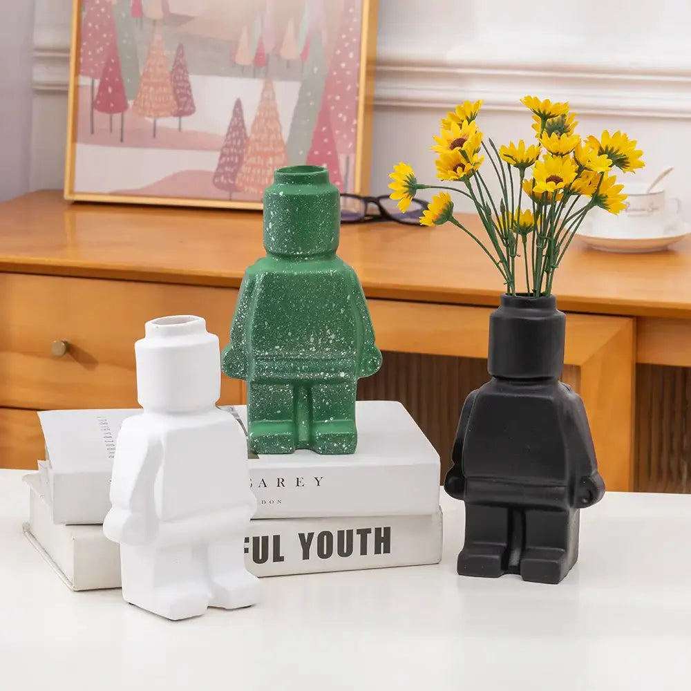 Green glittery ceramic robot vase holding yellow flowers in nordic style home decor by decorbites