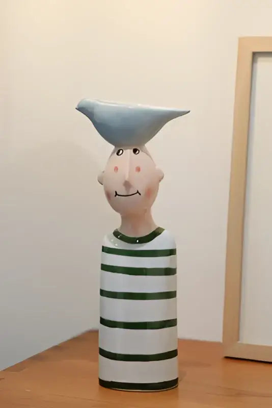 Whimsical ceramic vase set featuring a smiling man with pink cheeks wearing green stripes and a blue bird for home decor