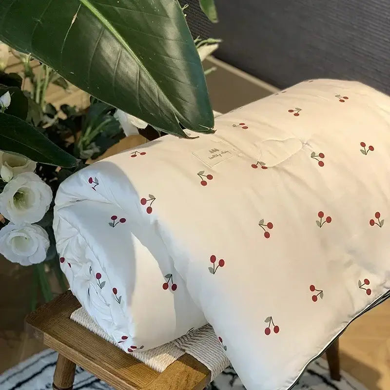 A soft off-white decorbites cherry lyocell fiber cooling blanket with red cherry patterns for child and adult use
