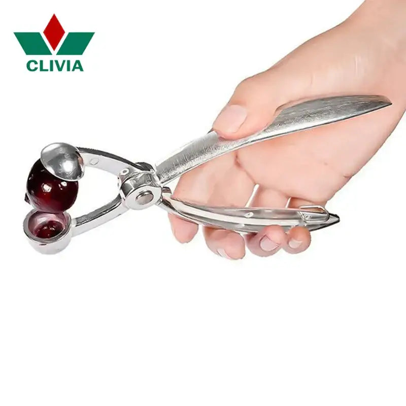 Silver metal decorbites cherry pitter with polished finish and two spherical chambers holding a dark red cherry