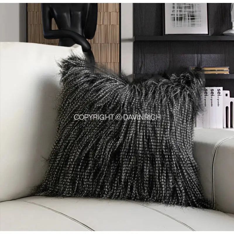 A plush black and silver faux fur pillow case with textured fringed edge on white leather sofa by decorbites chestnut brown wabi