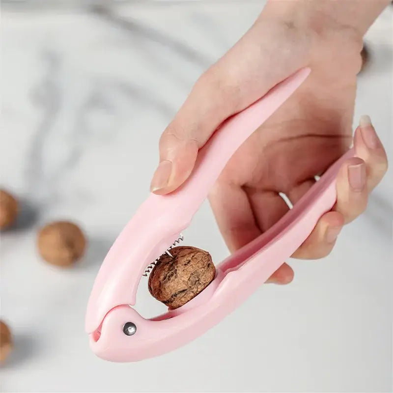 Pink plastic decorbites chestnut cracker holding a walnut for easy nut opening and shelling in the kitchen