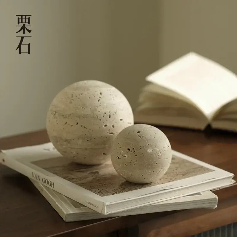 Two beige textured stone spheres with speckled surface atop books in DecorBites wabi sabi wind rock ornament figurines