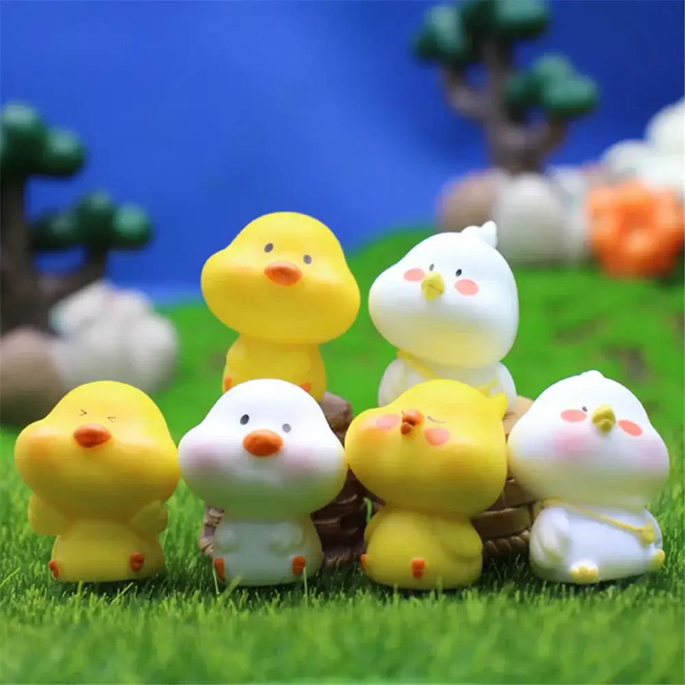 Adorable yellow and white decorbites chick doll figurines with orange beaks and feet in a miniature garden scene