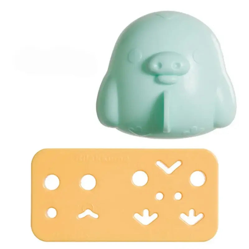 Mint green plastic penguin-shaped ice cube tray with orange stencil featuring facial expressions in decorbites chicken bear mold set