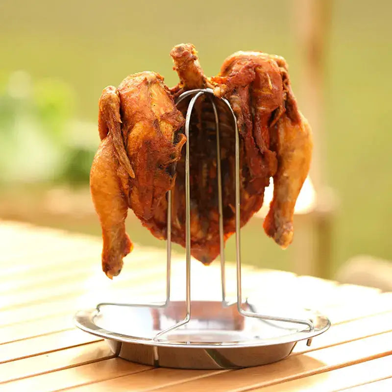 A golden-brown roasted chicken on a stainless steel decorbites chicken roaster rack with a matching circular base