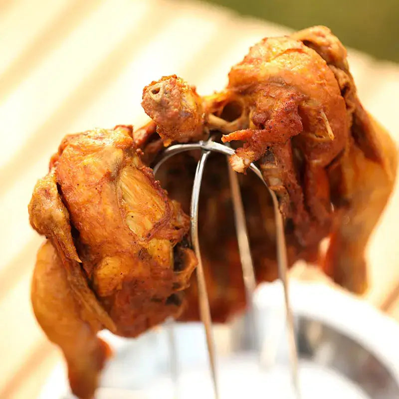 Golden-brown roasted chicken held by metal skewer with stainless steel decorbites chicken roaster rack for oven grilling