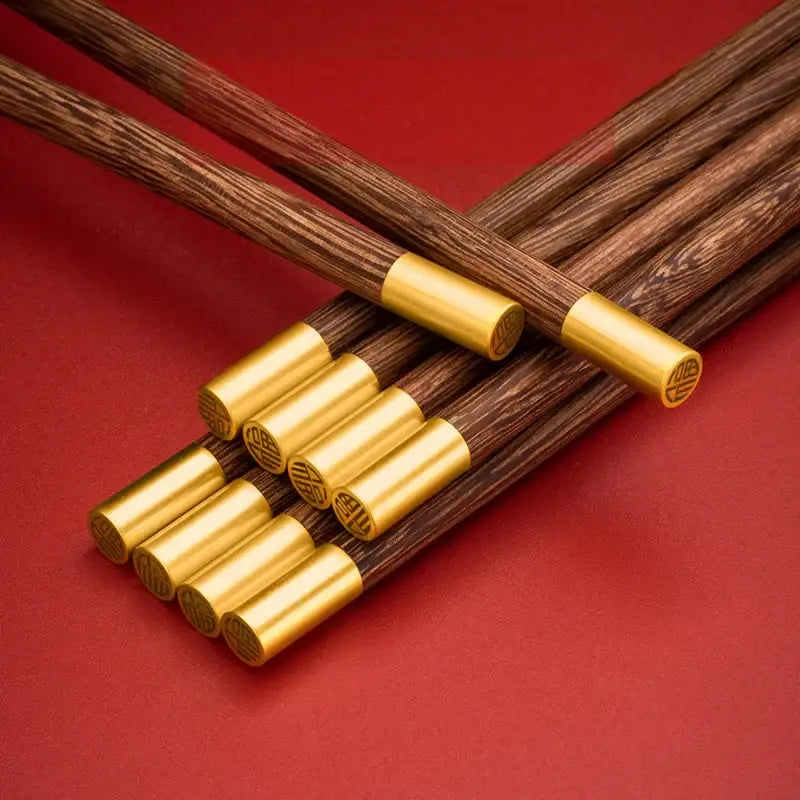 Set of elegant decorbites™ chicken-wing wood chopsticks with dark wood and gold metal caps engraved with chinese characters