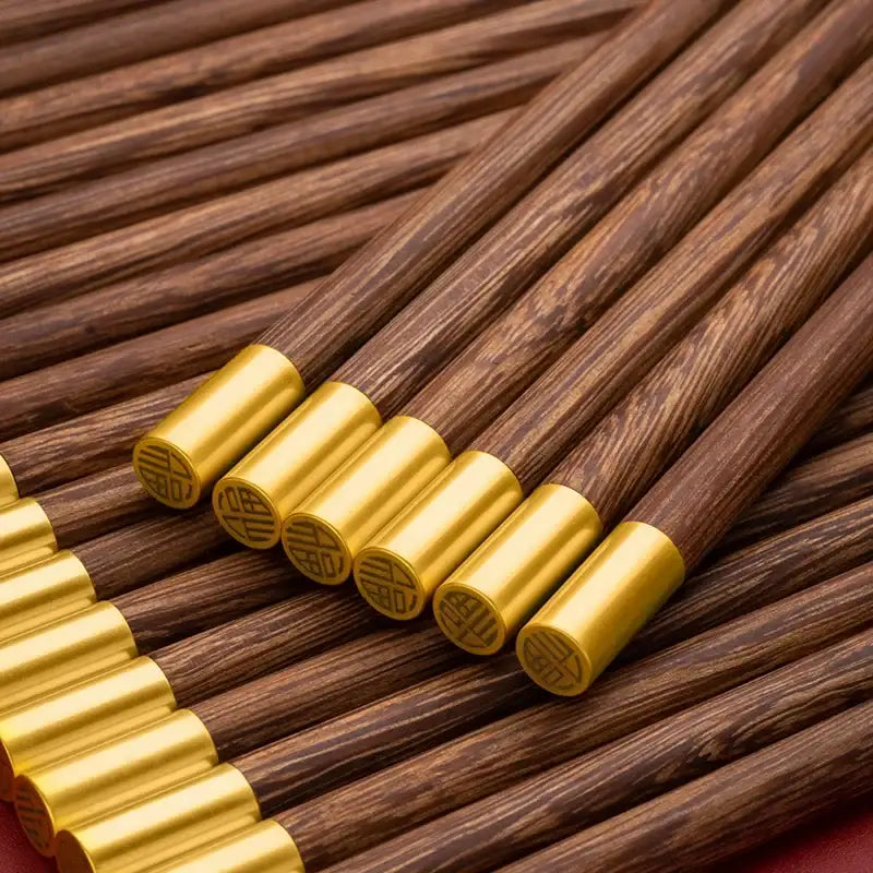 Dark brown chicken-wing wood chopsticks set with golden metallic caps engraved with chinese characters by decorbites
