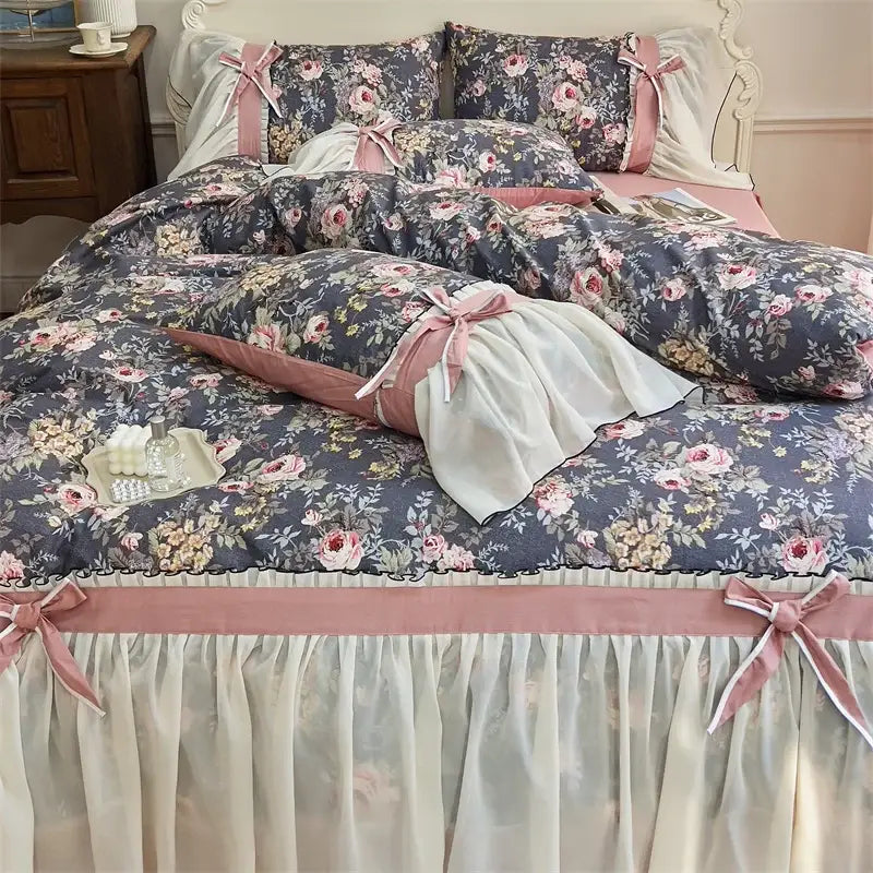 A soft dark gray floral bedding set with pink ribbon ties and a sheer white ruffled skirt from decorbites chiffon lace ruffles collection