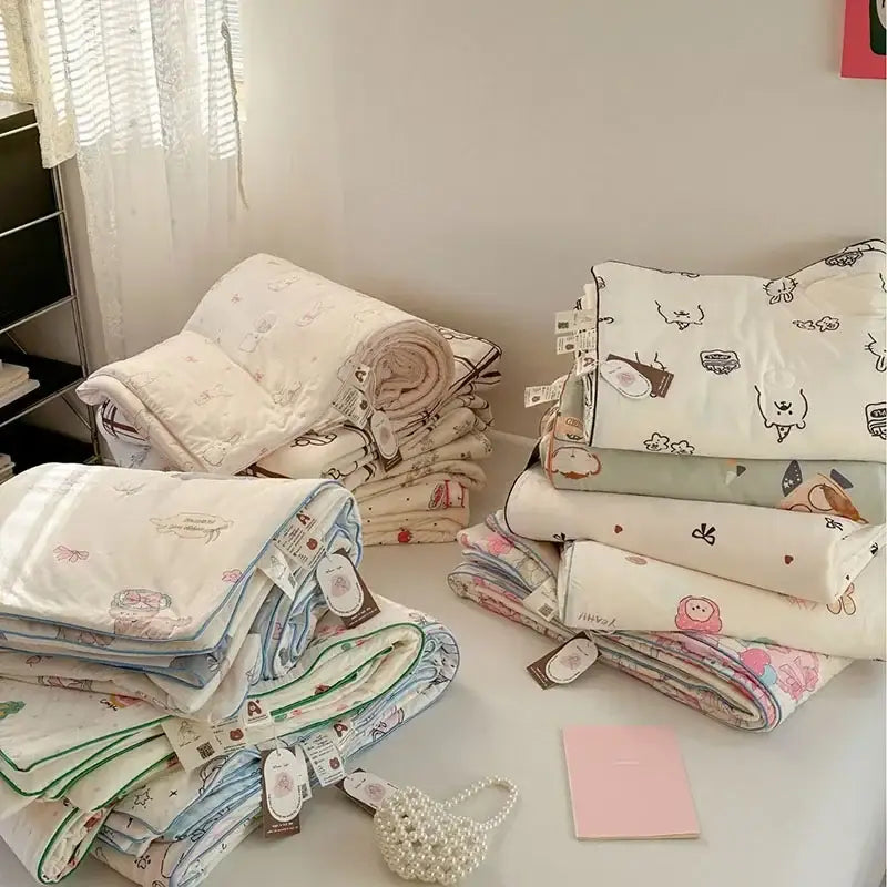 Stacks of soft pastel-colored quilted decorbites children cartoon cooling quilts with cute animal prints and embroidered borders