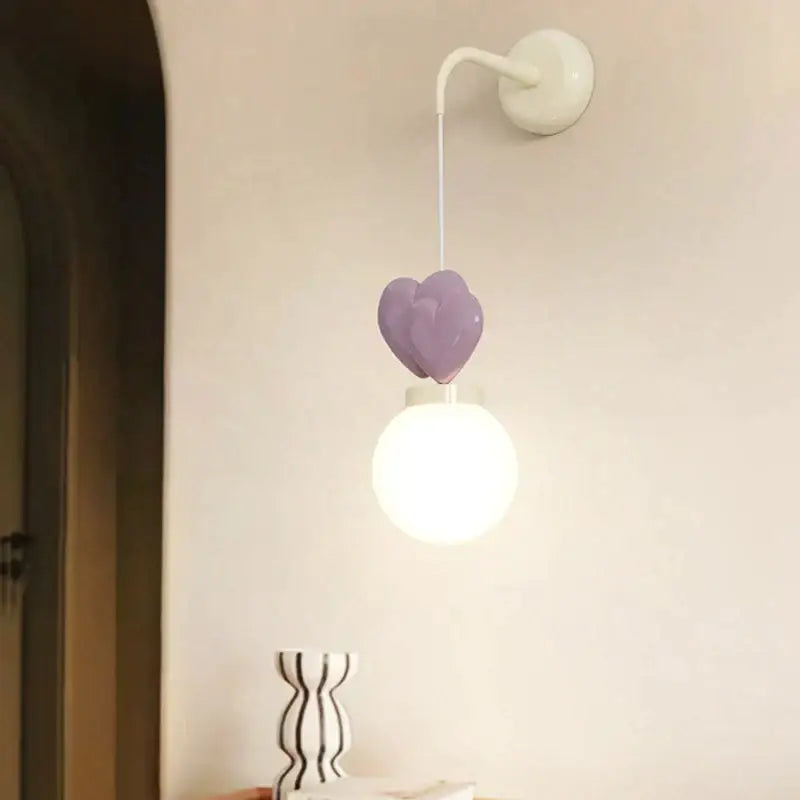 Purple heart-shaped ceramic love wall lamp with white spherical bulb for children’s nursery room decor by DecorBites™